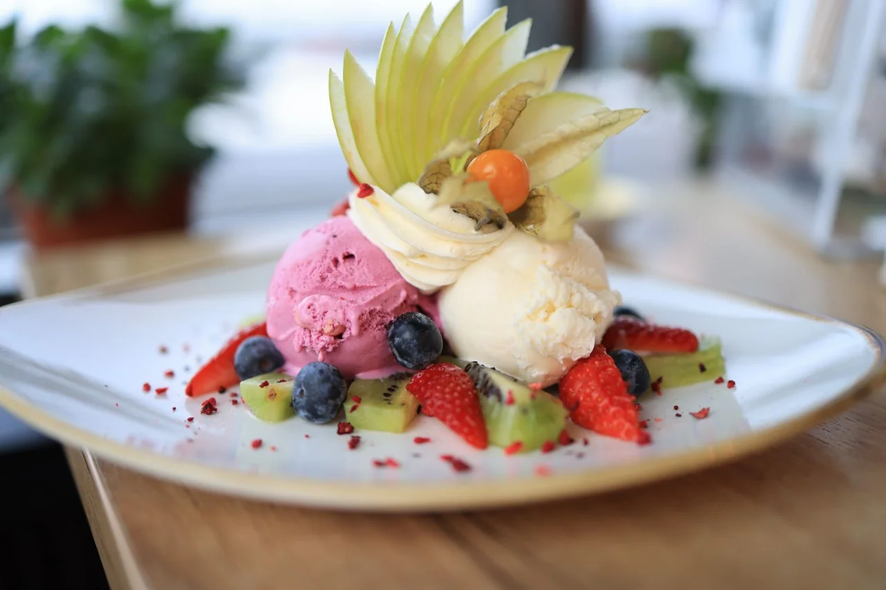 Architectural ice cream dessert bowl with fresh kiwi, blueberries and raspberry puree