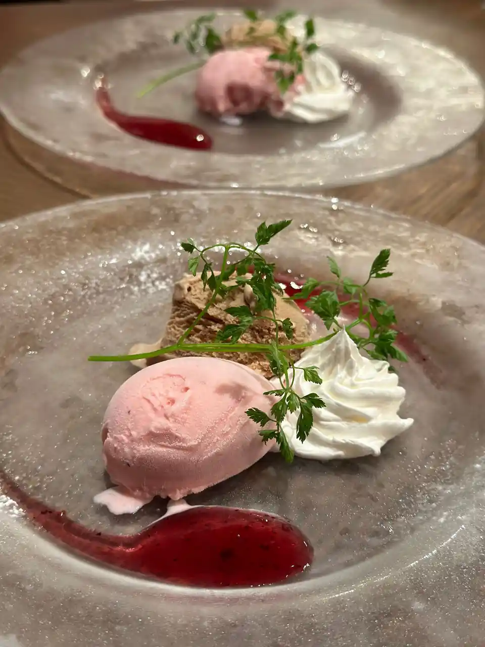 Plated artisan dessert with delicate pink raspberry gelato scoop and subtle confectionery finish on a bespoke ceramic dish