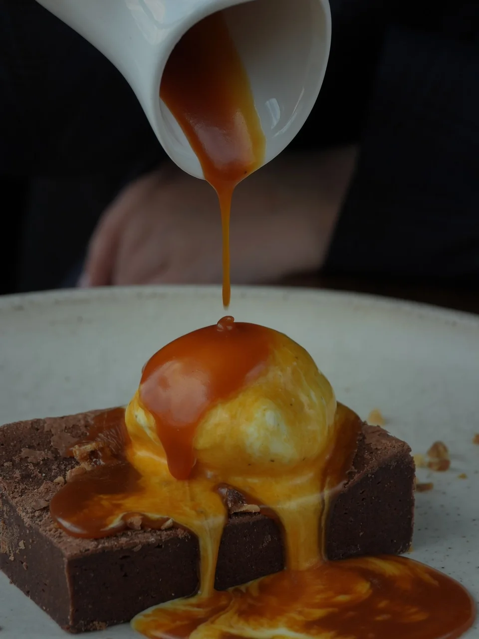 Decadent chocolate brownie dessert served warm with vanilla ice cream and caramel drizzle
