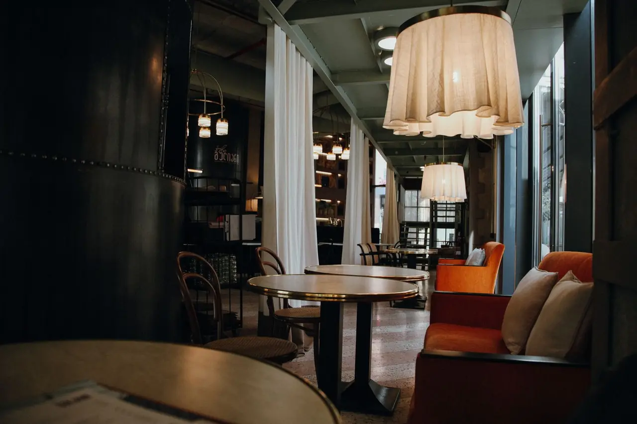 Warmly lit dining room with bespoke wooden tables, ambient pendant lights, and peaceful café atmosphere